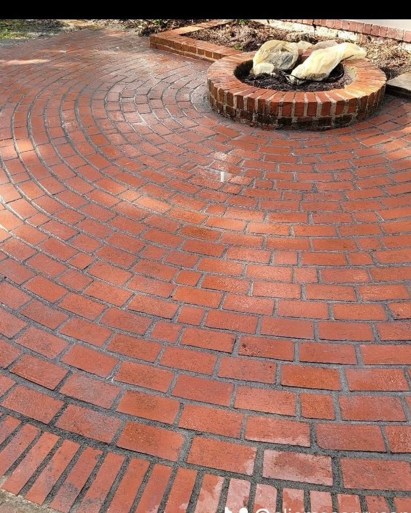 Brick walkway with herringbone center and red brick borders alongside a dirt path