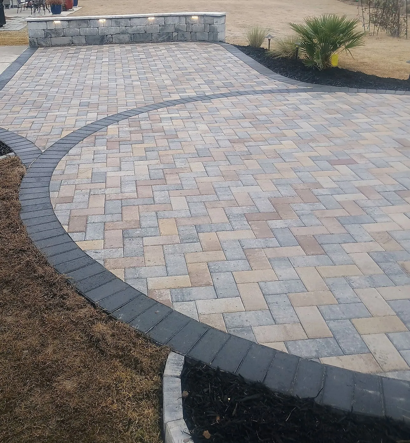 Fresh concrete driveway leading to a gray house with fenced sides